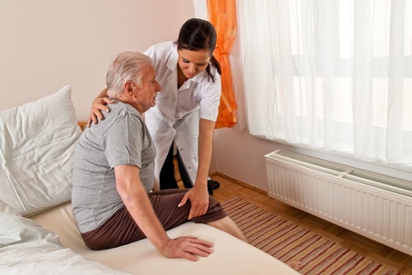 Female nurse helping an elderly man out of bed