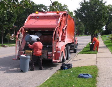 Garbage men putting trash in a garbage truck